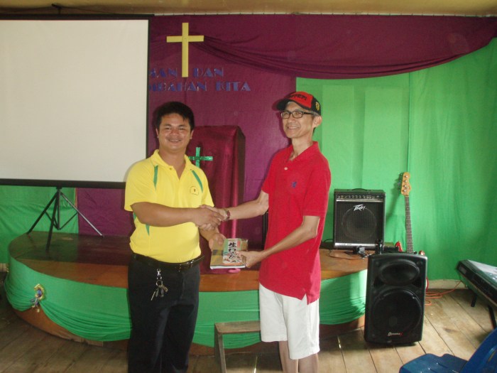 Elder William Ho handing over stationery packs for the students to Ps. Ishak